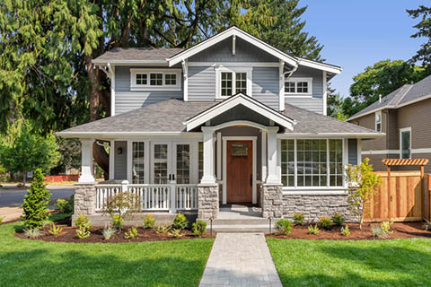 Two-story gray house with white trim, a covered porch, wooden front door, and a stone facade - https://murphyinsgrp.com/