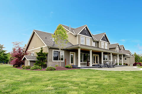 A large, inviting house with beige siding and multiple gables sits in a lush green yard - https://murphyinsgrp.com/